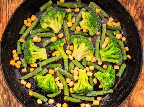 vegetables broccoli corn green beans in a cast iron skillet. View from above.