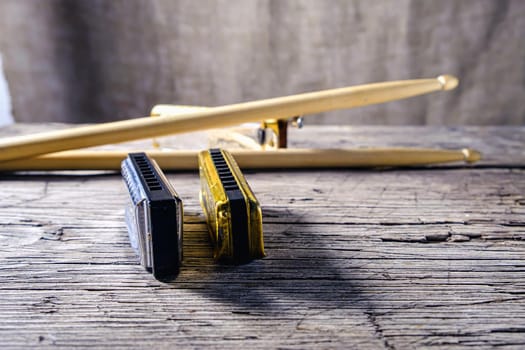 Musical instruments vintage harmonics diatonic and chromatic and drum sticks on old wooden desk. world music day. Horizontal orientation.