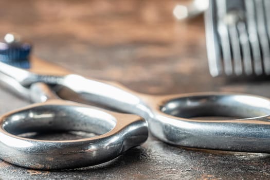 scissors for haircuts. Background part of a clipper in blur. Horizontal orientation. Rusty background. close-up.