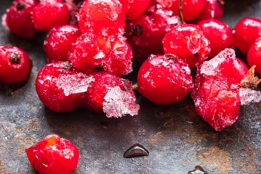 Frozen ice red currants pile lie on a rusty surface. horizontal orientation. close-up