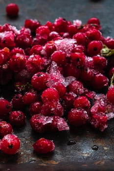 Frozen red currants pile lie on a rusty surface. dark. vertical orientation. close-up