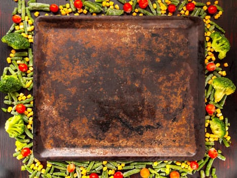 Food background with free space for text. broccoli, corn, green beans, tomatoes around a baking sheet. View from above.