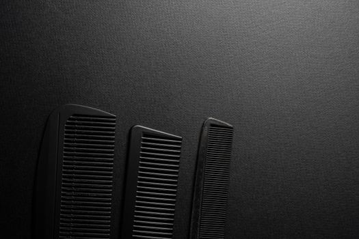 On a black surface are old barber tools. barber tools. three comb. black monochrome. frame. top view flate lay. copy space