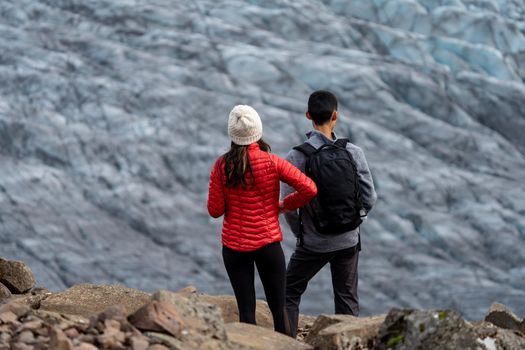 Unrecognizable tourist couple looking to the glacier, focus on foreground