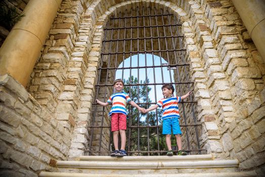 Young brothers near an ancient stone gate. Kids smiling and happy having leisure time on summer holiday.