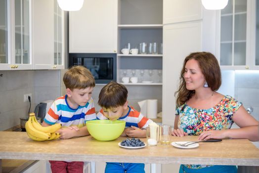 Young mother and her two kids at kitchen baking cookies.