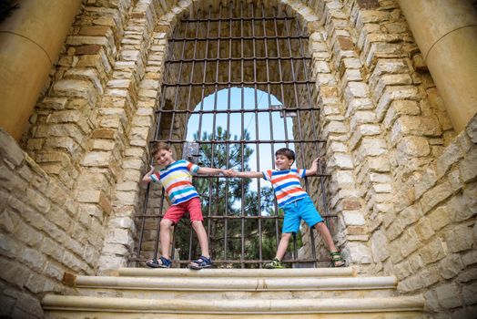 Young brothers near an ancient stone gate. Kids smiling and happy having leisure time on summer holiday.