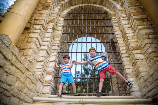 Young brothers near an ancient stone gate. Kids smiling and happy having leisure time on summer holiday.
