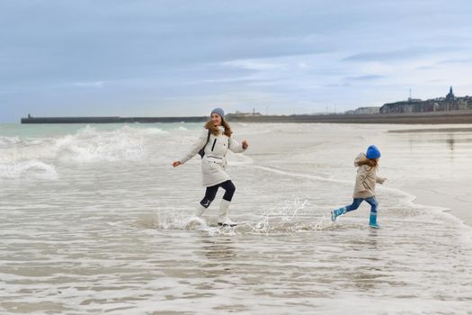 Mother and daughter run away from the waves on the Atlantic coast