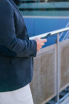 young business man looking phone near to office. Natural light in a sunny day.