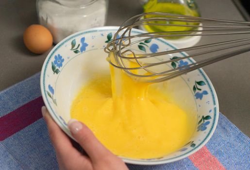 beating hen's eggs in a white bowl with a whisk for sweet or savoury festive culinary recipes