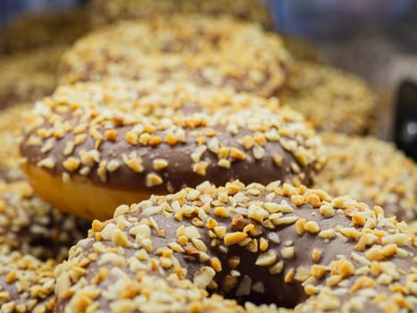 a group of delicious mouth-watering donuts with chocolate icing outside and sprinkled with chopped nuts.