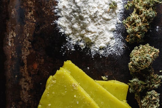 rustic cannabis butter and medical marijuana bud and flour on old rust metal dripping pan. old wooden background. horizontal orientation. close-up.