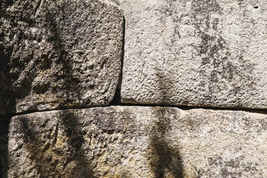 The ancient rusty old stone texture for background and design concepts. the shadow of the foliage on the rock. geology. Horizontal background