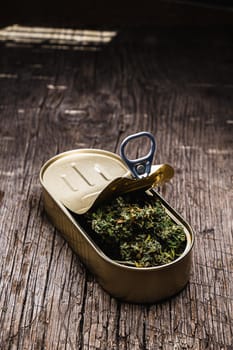 cannabis in a open tin can. on old wooden background. rustic