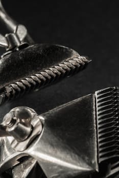 On a black surface are old barber tools.Two vintage manual hair clipper. black monochrome. Close-up. Barbershop background. contrast shadows. vertical orientation