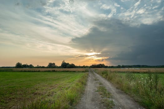 Rural road through fields and clouds during sunset, Nowiny, Poland