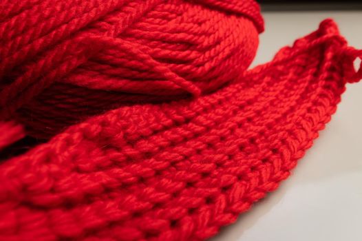 Close-up of an unknitted piece of wool next to a ball of yarn. Red wool yarn.