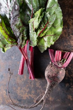 ugly food. Beets and beet leaves on a rusty beautiful metal surface. close-up. vertical orientation. flat lay. top view.