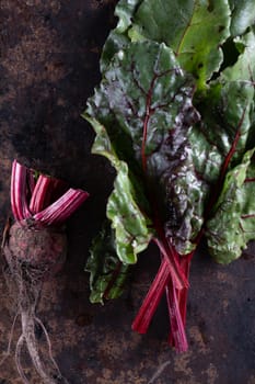 ugly food. Beets and beet leaves on a rusty beautiful metal surface. close-up. vertical orientation. flat lay. top view.