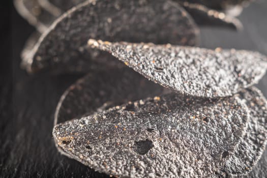 a lot of black chips with spices on a slate dish. close-up.