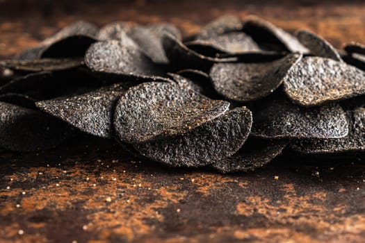 a lot of black chips with spices on an old rusty baking sheet