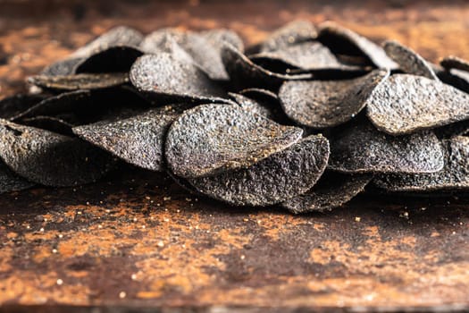 a lot of black chips with spices on an old rusty baking sheet