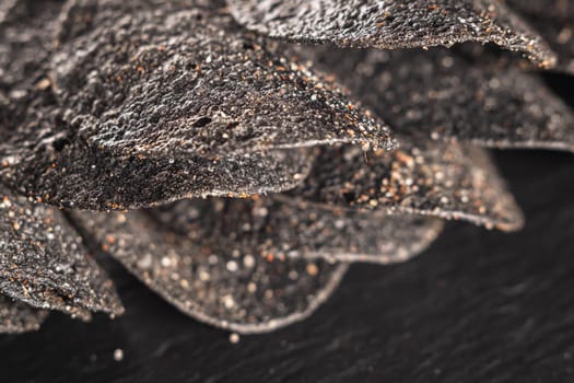 a lot of black chips with spices on a slate dish. close-up.