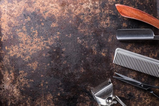 Old barber tools on an old beautiful rusty surface. A razor, shaving brush, comb, hairdressers scissors, and a clipper. horizontal orientation. copy space. dark photo. flat lay. top view.