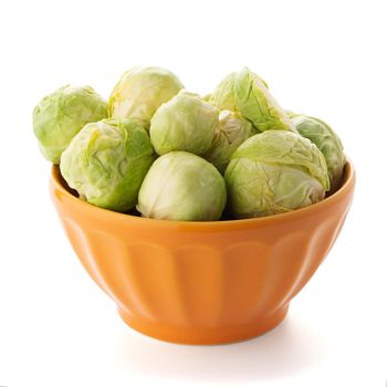 Fresh brussels sprouts on orange ceramic bowl isolated on white background.