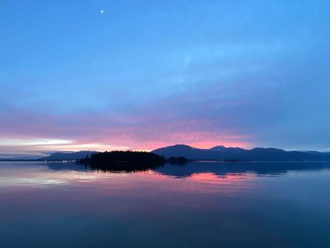 Beautiful pink sunset over mountains located on Vancouver Island with reflection onto water, Gulf Islands, British Columbia, Canada