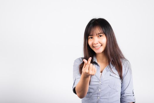 Woman standing her smile confidence showing mini heart sign with her finger isolated white background, Asian happy portrait beautiful young female send love and happy valentine in studio shot