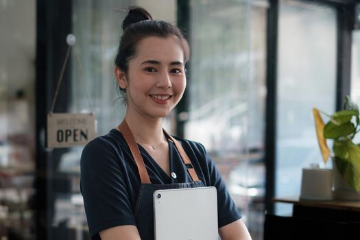 Portrait of asian woman barista cafe owner smile while cafe open. SME entrepreneur seller business concept