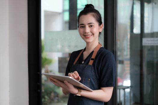 Portrait of asian woman barista cafe owner smile while cafe open. SME entrepreneur seller business concept