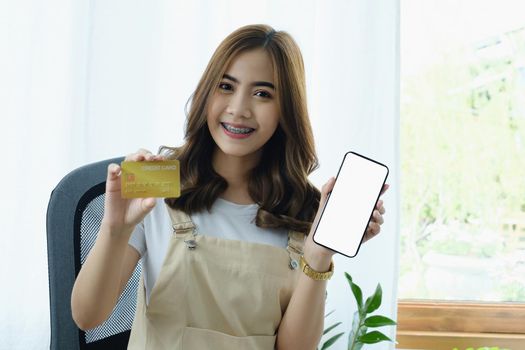 Young woman showing smartphone blank screen and credit card. Shopping online and Online payment concept.