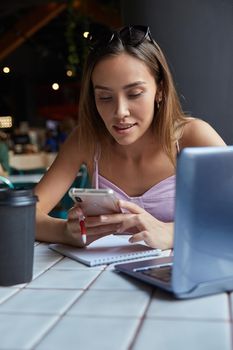 young well dressed asian woman sitting at table, using her smartphone. beautiful lady surfing internet on cell phone at cafe, chatting online. modern communication technology, distant work, remote job