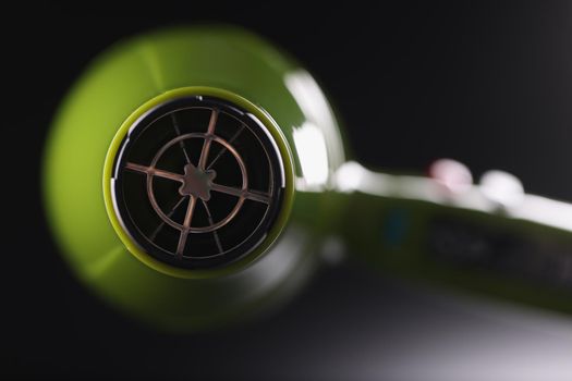 Close-up of a green hair dryer on a gray background, rear view, blurry. Hair dryer accessories, clean filter, barbershop equipment