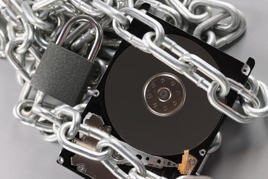 The hard drive is wrapped with a chain with a padlock, close-up. Cyber security, hacker attack, data protection