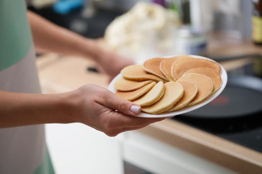 Close-up of a woman's hand with a plate of pancakes. Cooking food at home, vegan bakery, sweet homemade