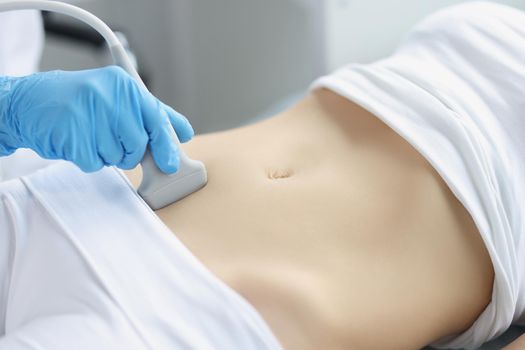 Doctor's hands on a woman's stomach, ultrasound of the abdominal cavity, close-up. Diagnosis of diseases of the genitourinary system