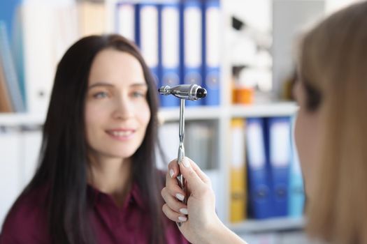 A woman is watching the hammer of a neurologist, her face is close-up, blurry. Diseases nervous system, psychiatric consultation