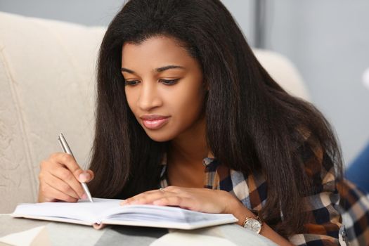 girl on the sofa makes notes in a notebook, close-up. Self-development, motivation for learning