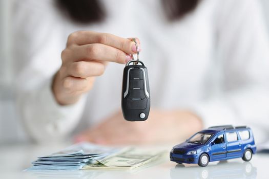 Female hands hold an electronic auto key, close-up. Car purchase, cash payment, rental, vehicle loan