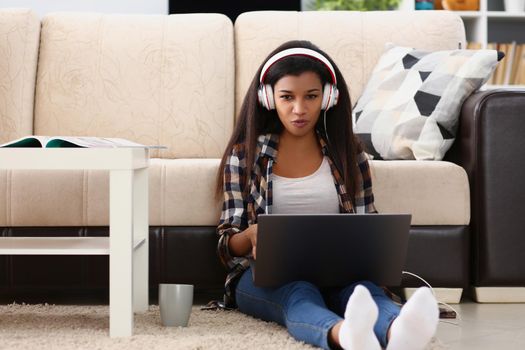 girl in headphones sits at home on the floor with a laptop, close-up. Online learning, training during a pandemic