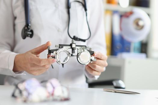 The doctor holds an optical trial spectacle frame, close-up. Optometrist's office, vision correction