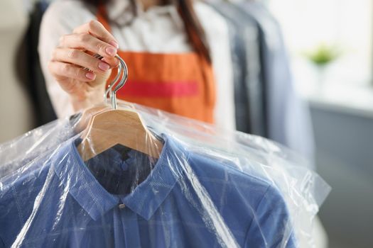 Laundry worker keeps things on a hanger, close-up, blurry. Dry cleaning and laundry service, housework