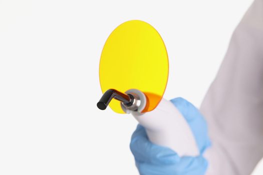 A gloved hand holds a led curing light for filling teeth, close-up. Dental equipment and instruments