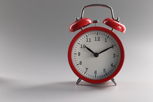 Close-up of a red alarm clock with bells on a gray background. Wake up time signal. Retro style, home decoration