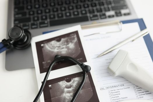 The workplace of the ultrasound doctor. On the table is an ultrasound scan and a patient card, close-up