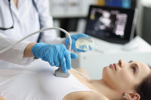 Doctor's hands on a woman's chest, ultrasound chest, close-up. Preparation for breast augmentation, examination by a mammologist